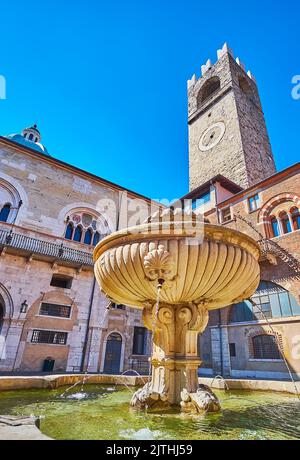 La fontaine médiévale en pierre dans la cour du Palazzo Broletto avec Torre del pegol en arrière-plan, Brescia, Italie Banque D'Images