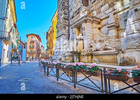 La fontaine Pallata en pierre médiévale ou la fontaine des rivières (Fontana dei Fiumi) avec des décors sculptés et des cyclamens en pots au premier plan, Banque D'Images