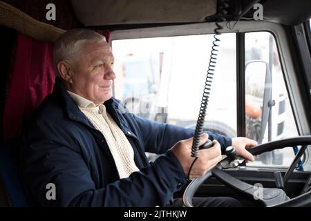 Conducteur âgé assis dans la cabine d'un gros camion moderne Banque D'Images