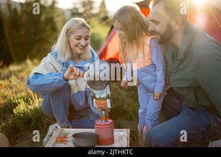 Couple avec petite fille de cuisine de nourriture sèche pour la randonnée au camping Banque D'Images