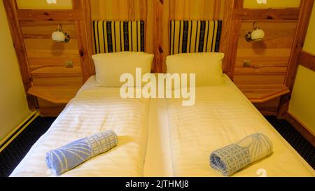 Chambre à coucher pour les clients avec lits doubles dans la maison de campagne dans les moulins en bois et le sol, gros plan. Banque D'Images