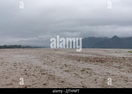 Eau d'inondation sale qui coule rapidement dans une rivière de montagne Banque D'Images