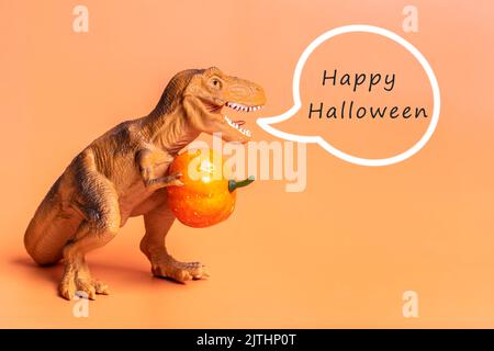 Jouet dinosaure Tyrannosaurus tenant le potiron dans ses pattes isolées sur fond orange carte de vœux de vacances Joyeux jour d'Halloween, Hello Autumn Creative Banque D'Images