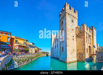 SIRMIONE, ITALIE - 10 AVRIL 2022 : le principal site historique de Sirmione - Castello Scaligero avec des maisons de couleur et douves de la rue via Dante Banque D'Images