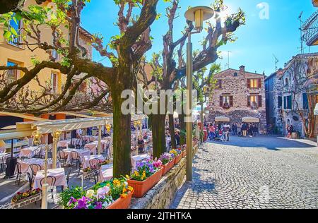 SIRMIONE, ITALIE - 10 AVRIL 2022 : rue via San Salvatore avec restaurants, parterres de fleurs de couleur pansy et vieilles maisons en pierre, sur 10 avril à Sirmio Banque D'Images