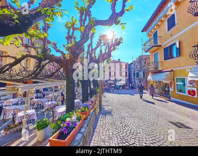 SIRMIONE, ITALIE - 10 AVRIL 2022 : l'allée piétonne de la rue San Salvatore avec des restaurants, de grands arbres et un soleil éclatant, sur 10 avril à Sirmione Banque D'Images