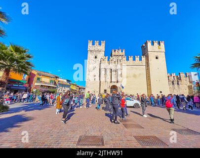 SIRMIONE, ITALIE - 10 AVRIL 2022 : la place Piazza Castello surpeuplée avec de vieilles maisons, des restaurants en plein air et le château historique de Scaligero avec Tall towe Banque D'Images