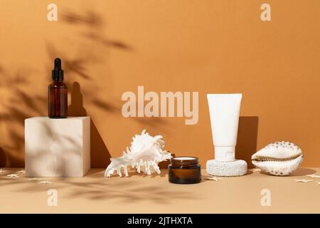 Une maquette de cosmétiques naturels et de sérum sur des supports en bois, des ombres dures du soleil et des coquilles. Copier l'espace. Le concept des cosmétiques de protection solaire, des soins du corps et de la peau. Banque D'Images