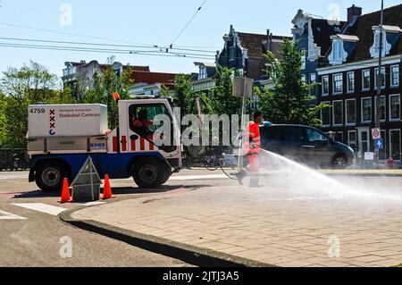 Les nettoyeurs de rue utilisent un nettoyeur haute pression puissant sur un camion pour nettoyer la piste à Amsterdam, pays-Bas Banque D'Images