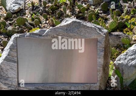 Plaque vierge sur la pierre au milieu du jardin de cactus avec des rochers. Plaque commémorative dans le parc. Vider le panneau d'affichage sur le mur. Banque D'Images