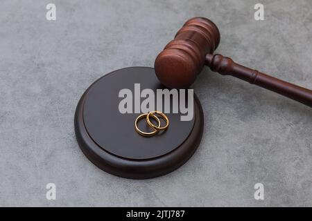 Thème droit. Jugez les anneaux de mariage de gavel sur fond gris en pierre de béton. Procédure de divorce. Maillet de juge qui décide du divorce de mariage, de l'accord matrimonial, des légalités du divorce Banque D'Images