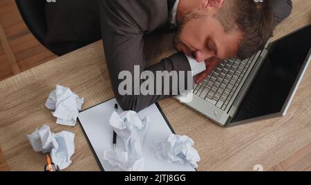 Ennuyé homme d'affaires endormi programmeur développeur de logiciel dans le costume formel s'endormir après le travail de routine sur ordinateur portable au bureau. Épuisé travailleur indépendant fatigué. Surtravaillé Banque D'Images