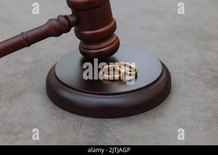 Thème droit. Jugez les anneaux de mariage de gavel sur fond gris en pierre de béton. Procédure de divorce. Maillet de juge qui décide du divorce de mariage, de l'accord matrimonial, des légalités du divorce Banque D'Images