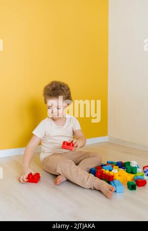 L'enfant joue avec des cubes colorés à la table. Kid a du plaisir et construit à partir de blocs de construction brillants. Apprentissage précoce. Jouets éducatifs Banque D'Images