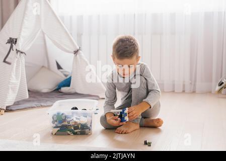 Garçon enfant joue avec des jouets, collecte un constructeur dans une chambre confortable pour enfants Banque D'Images