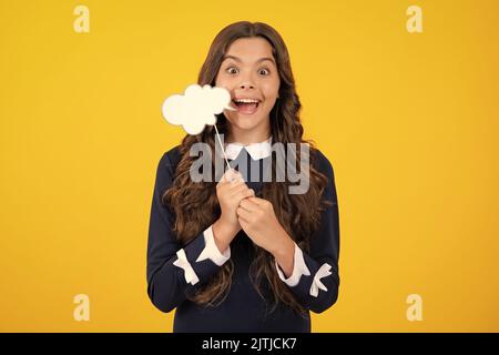 Adolescente fille tenant la bulle de pensée, le nuage de commentaire sur fond jaune. Banque D'Images