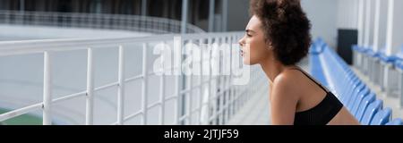 Vue latérale de la african american sportswoman en noir sur le stade, bannière Banque D'Images