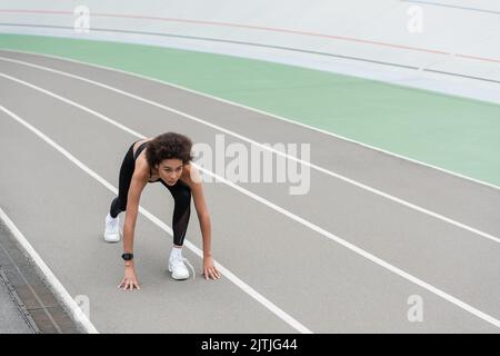 jeune femme afro-américaine en baskets blanches debout au démarrage bas pose sur la piste Banque D'Images