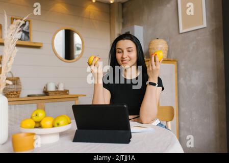 Happy Athletic woman blogger fitness trainer ou nutritionniste tient une vidéo conférence sur la saine alimentation sur un ordinateur portable dans la cuisine Banque D'Images