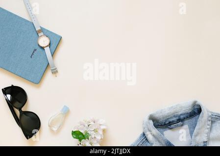 Rédaction d'un concept de blog. Bloc-notes, accessoires pour femmes, vêtements, montres-bracelets, lunettes de soleil, fleurs sur fond beige. Vêtements de mode et de beauté. Banque D'Images