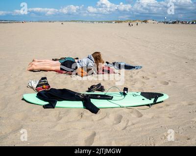 Un couple est vu s'allonger sur le sable après le surf. La plage de Hoek van Holland est de 250 mètres de large et de 3,5 km de long, située dans l'angle sud-ouest de la Hollande, d'où le nom. Les dunes avec des pistes cyclables et de randonnée librement accessibles se trouvent derrière elles. Pendant la Seconde Guerre mondiale, le crochet était l'un des endroits les plus importants pour la Wehrmacht à cause de son port, qui comprenait une partie importante et stratégique du mur de l'Atlantique. En raison du beau temps de ce week-end, les Hollandais et les touristes étrangers pouvaient profiter de la plage en marchant, en nageant et en pêchant. Banque D'Images