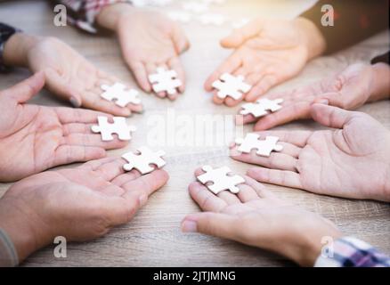 Les mains de diverses personnes assemblant le puzzle, l'équipe des jeunes ensemble des pièces à la recherche de la bonne correspondance, aider à soutenir le travail d'équipe pour trouver le commun ainsi Banque D'Images