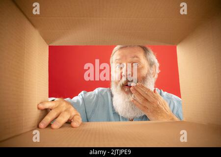Soyez modeste. Homme barbu en train de déballer, d'ouvrir la boîte de carton et de regarder à l'intérieur. Livraison, surprise, cadeau, émotions concept. Banque D'Images