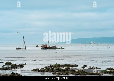 paysage marin avec une épave au premier plan et un petit bateau de pêche en mer en arrière-plan Banque D'Images