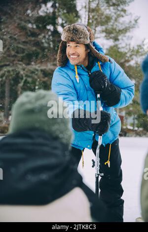 Heureux homme mûr debout avec la tarière à glace pendant l'hiver Banque D'Images