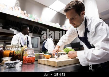 Chef hacher des oignons sur la planche à découper dans la cuisine commerciale du restaurant Banque D'Images