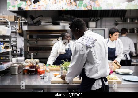 Chefs multiraciaux préparant des plats dans la cuisine du restaurant Banque D'Images