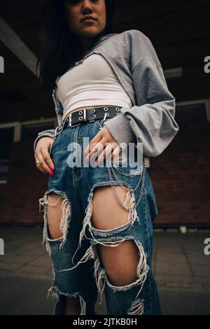 Section médiane de la jeune femme en jeans déchirés debout sur le sentier Banque D'Images