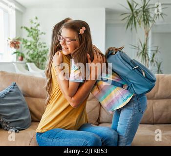 enfant mère famille éducation école fille maison fille sac à dos aider parent se préparer primaire adolescent matin hug amour aider ensemble Banque D'Images