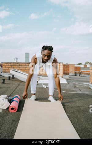 Toute la longueur du jeune homme qui règle le tapis d'exercice sur le toit Banque D'Images