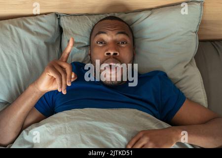 Black Guy pointant le doigt vers le haut ayant l'inspiration couché dans la chambre Banque D'Images