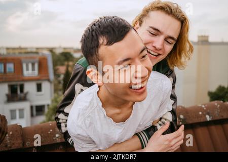 Un jeune homme plein de joie s'embrassant avec un ami tout en appréciant ensemble sur le toit Banque D'Images