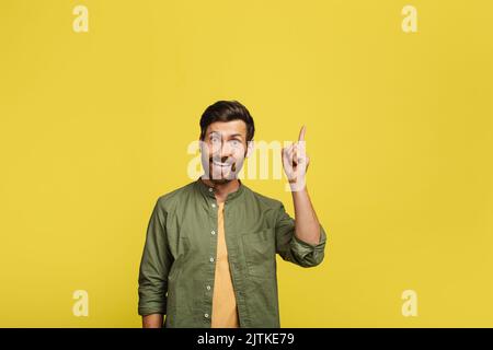 Un homme positif qui vit un moment AHA, qui a une idée créative ou qui pointe le doigt vers le haut sur l'espace de copie sur fond jaune Banque D'Images