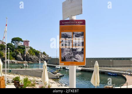 Un panneau touristique expliquant l'histoire du petit port (Porticciolo) de Nervi avec la jetée et la falaise en arrière-plan en été, Gênes, Ligurie Banque D'Images