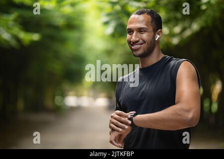 Un jeune sportif afro-américain élégant a mis en place son tracker de fitness Banque D'Images