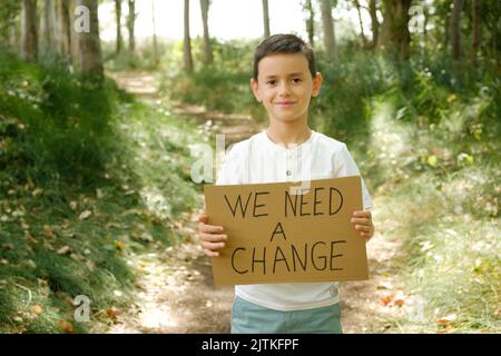 l'enfant tient un signe entre ses mains avec le message « nous avons besoin d'un changement » Banque D'Images