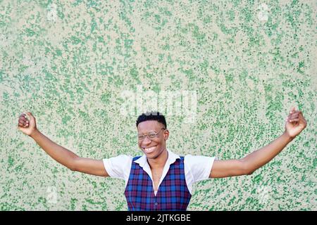 un jeune homme afro-américain lève les bras en mode victoire ou célébration en regardant la caméra Banque D'Images