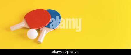 Kit de tennis de table sur fond jaune. Raquettes de ping-pong rouges et bleues et balle blanche. 16:6 bannière web. Banque D'Images