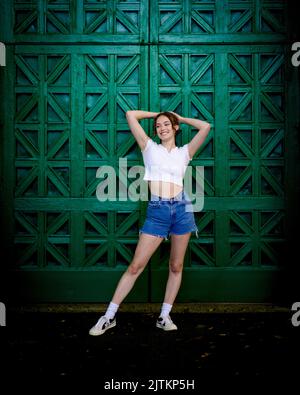 Portrait de jeune femme amusant devant une grande porte verte ornée Banque D'Images