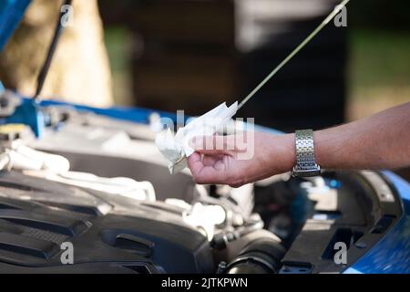 Gros plan d'un mécanicien qui vérifie le niveau d'huile dans la voiture Banque D'Images