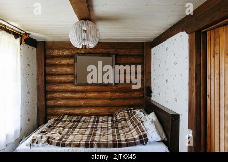 Tableau maquette de cadre haging sur un mur de bois dans une chambre rustique avec un lit double. Collez votre image ici. Banque D'Images