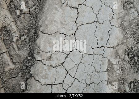 Texture de saleté sèche grise fissurée avec impression des pneus sur les côtés. Vue de dessus. Banque D'Images