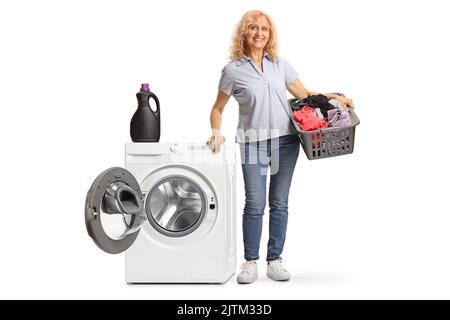 Portrait complet d'une femme tenant un panier à linge près d'un lave-linge isolé sur fond blanc Banque D'Images