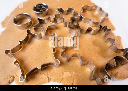 Couper les biscuits avec de la moisissure métallique de la pâte à croûte courte. Un métal se forme sous forme de flocons de neige pour faire du pain d'épice pour Noël. Banque D'Images