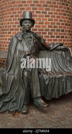 Statue en bronze de l'auteur danois H C Andersen assis sur un banc devant un mur de briques rouges, Odense, Danemark, 28 août 2022 Banque D'Images