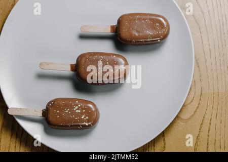 Crème glacée au cupcake et crème au chocolat arrosée de poudre d'or. Biscuits aux pépites de chocolat sous forme de crème glacée sur une assiette. Vue de dessus Banque D'Images